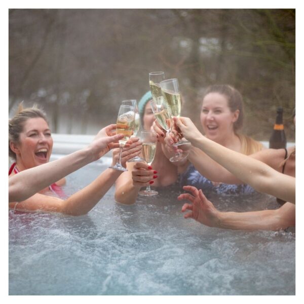 Group celebrating with champagne in hot tub