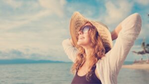 woman in sun hat smiles on beach