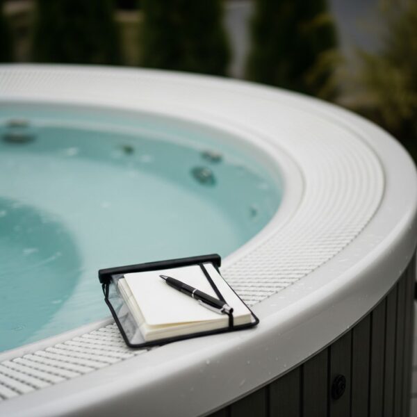 waterproof journal and pen resting on the edge of a calm hot tub